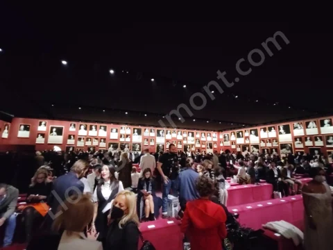 Guests gathering in a fashion-show hall lined with framed portraits.