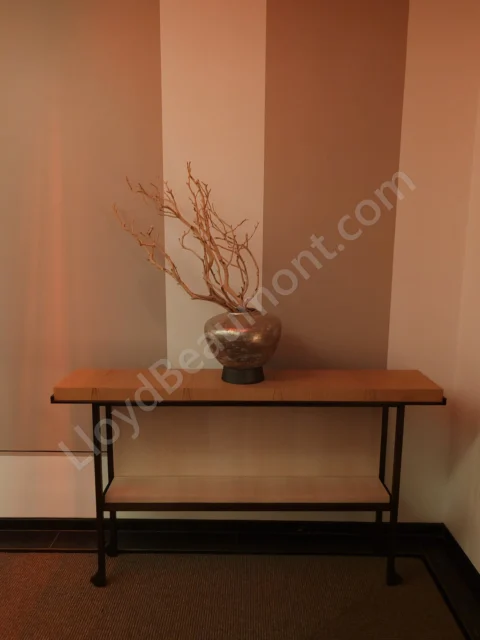 Minimalist hotel console table with a bronze vase and sculptural branches.