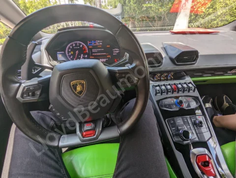 Lamborghini cockpit with a black steering wheel, digital instruments, and vivid green upholstery.