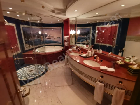 Luxurious bathroom with a round soaking tub, gilded fixtures, marble flooring, and blue mosaics.