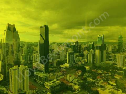 Modern city skyline viewed through yellow-tinted glass beneath a cloudy sky.