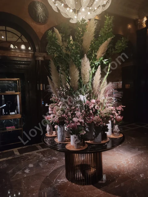 Dramatic floral display beneath a crystal chandelier in a richly colored marble lobby.