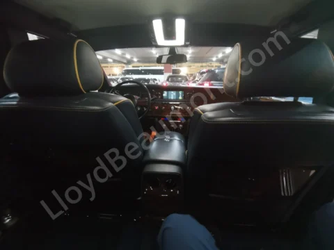 View from the rear seat of a luxury car with black leather upholstery and wood trim.